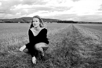 Portrait of woman crouching on field