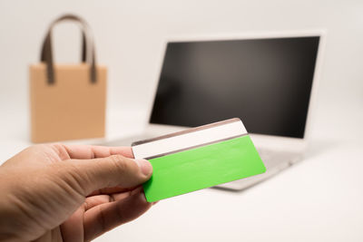 Cropped hand of woman holding box against white background