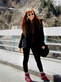 Full length portrait of young woman standing against building