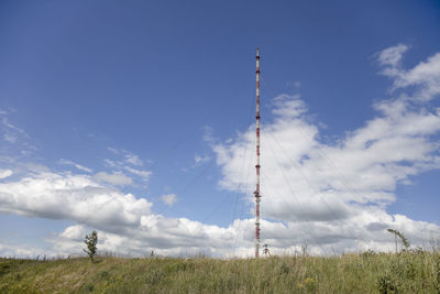 Low angle view of communications tower on field against sky