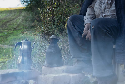 Low section of man sitting by kettles