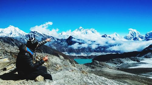 Man pointing at mountains against sky