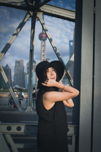 Portrait of young woman standing against built structure in city