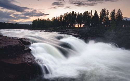 Scenic view of waterfall against sky during sunset