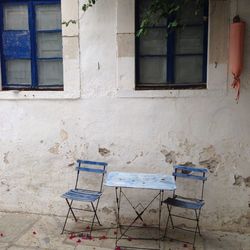 Empty chairs and tables against window in old building