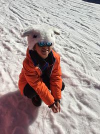 High angle portrait of boy crouching on snow during winter