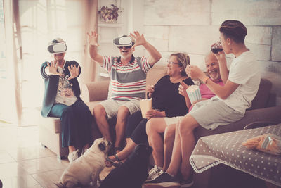 Senior couple wearing virtual reality simulator with family at home