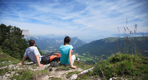 People sitting on mountain against sky