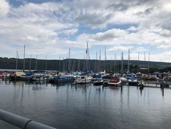 Boats moored at harbor against sky