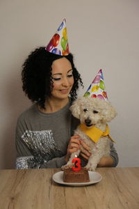 Smiling young woman celebrating birthday of dog 