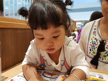 Close-up of girl reading book at table