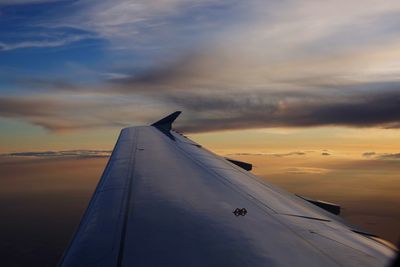 Airplane wing against sky during sunset