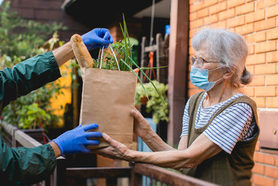 Midsection of woman holding umbrella while standing against plants in yard