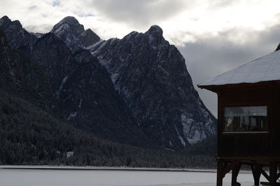 Stilt house over snowy field against snowcapped mountains