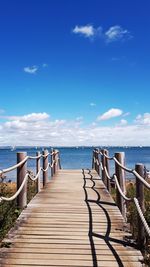 Wooden footpath leading to sea against sky