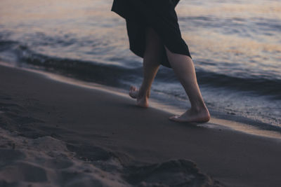 Low section of woman walking at beach