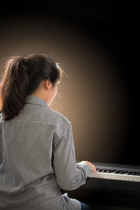 Rear view of woman playing piano