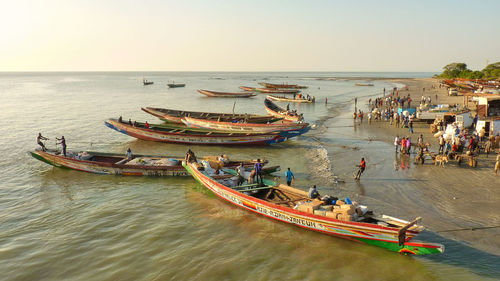 People with boats at gambia river against clear sky