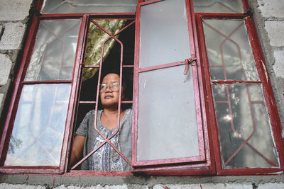 Low angle view of woman standing by window