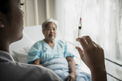 Female doctor with senior patient holding syringe