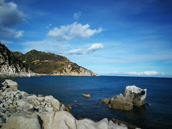 Rocks by sea against blue sky