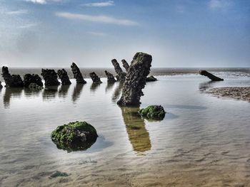 Scenic view of rocks on sea against sky