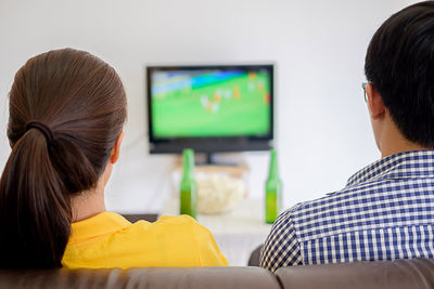 Rear view of people watching tv at home