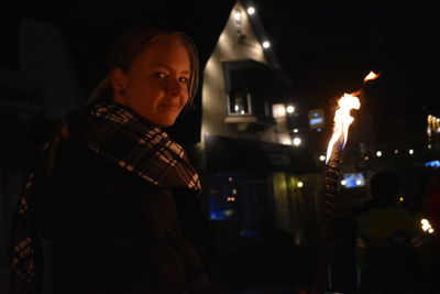 Portrait of man standing against illuminated fire at night