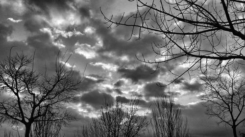 Low angle view of bare tree against cloudy sky