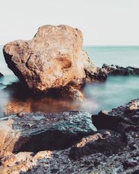 Rock formation in sea against sky