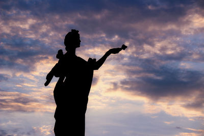 Low angle view of silhouette statue against sky