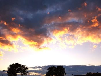 Low angle view of silhouette trees against dramatic sky