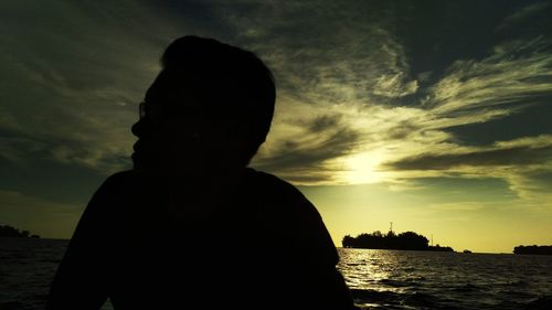 Silhouette man standing by sea against sky during sunset