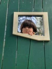 Portrait of cute boy looking through window