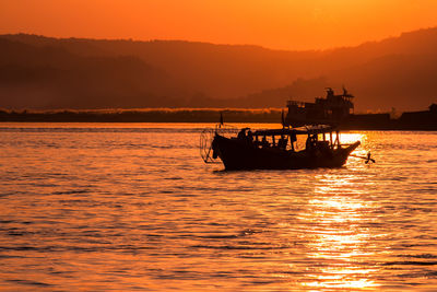 Silhouette boat in sea against sky during sunset