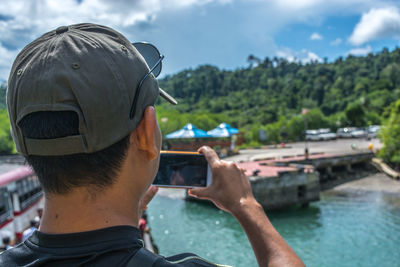 Rear view of young man photographing against sky