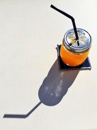 High angle view of orange juice in jar at table on sunny day