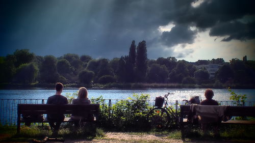 People sitting on bench by lake