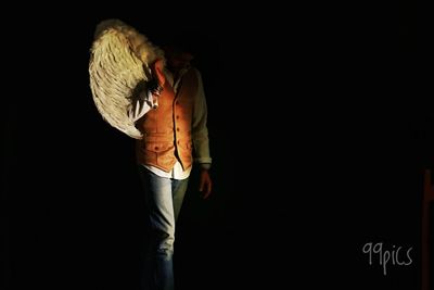 Midsection of woman standing against black background