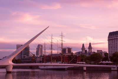 Bridge over river with buildings in background at sunset