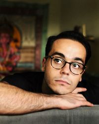 Young man wearing eyeglasses while looking away at home