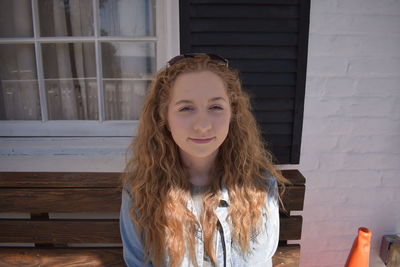 Portrait of beautiful young woman standing against wall