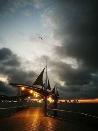 Illuminated suspension bridge over river against sky