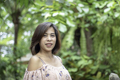Portrait of smiling young woman against trees in forest