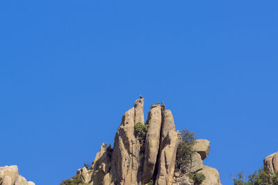 Low angle view of rock formation against clear blue sky