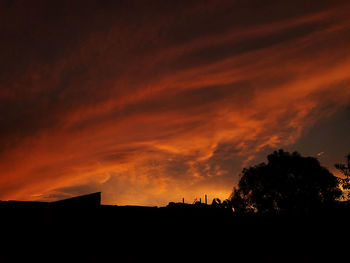 Low angle view of silhouette trees against dramatic sky