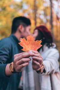 Close-up of hand holding maple leaf during autumn