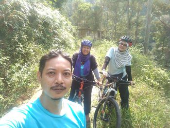 Portrait of smiling young man riding bicycle in forest