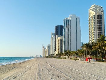 Modern buildings by sea against clear blue sky