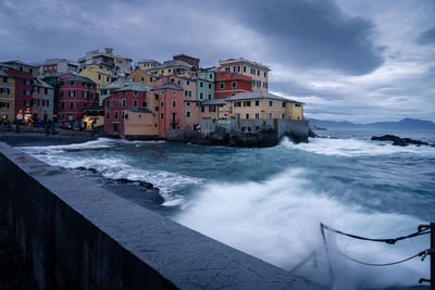 Buildings by sea against sky